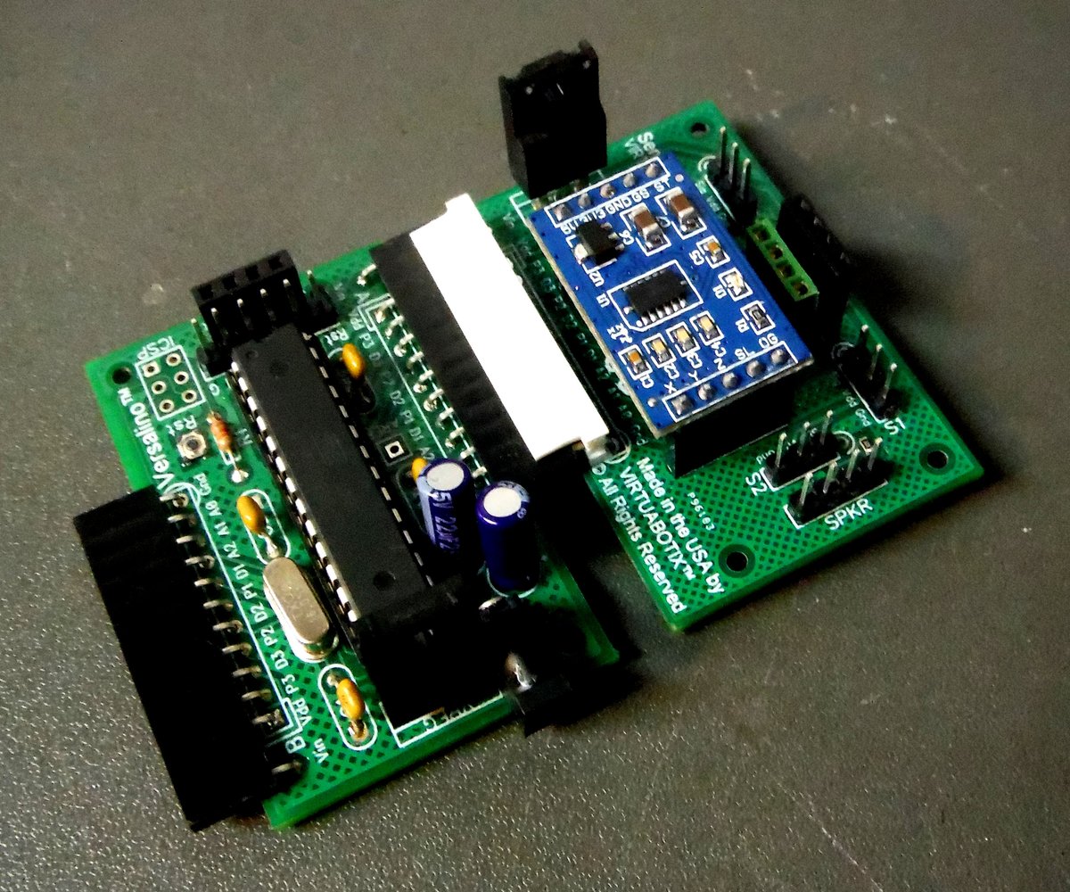 A Versalino Uno board with a blue Virtuabotix accelerometer module plugged in, resting on a gray surface.