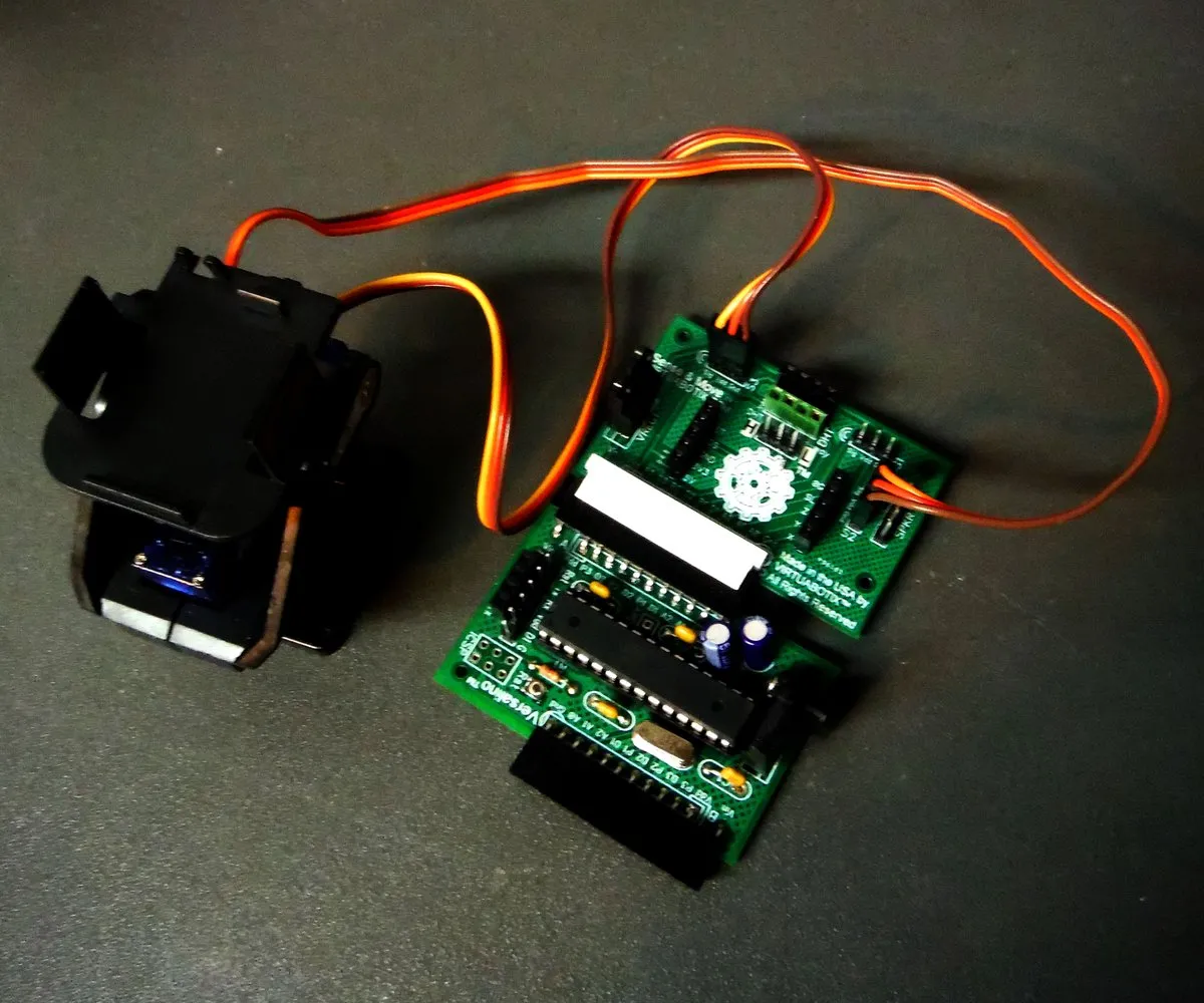 A Versalino Sense & Move board wired to a pan-tilt servo bracket, on a dark surface.
